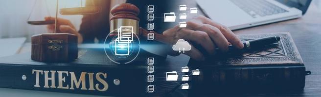 Justice and law concept.Male judge in a courtroom with the gavel, working with, computer and docking keyboard, eyeglasses, on table in morning light photo