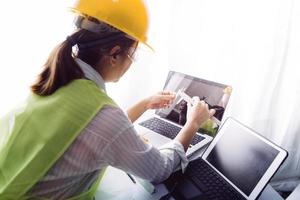 Two colleagues discussing data working and tablet, laptop with on on architectural project at construction site at desk in office photo