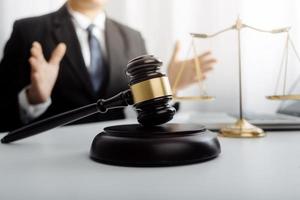 Justice and law concept.Male judge in a courtroom with the gavel, working with, computer and docking keyboard, eyeglasses, on table in morning light photo