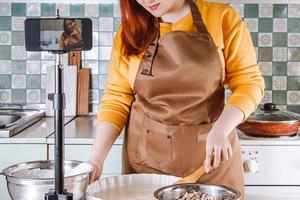 bloguera moderna haciendo un video para un blog de comida. mujer joven cocinando comida en la cocina de casa. foto