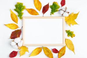 Empty frame mock up on white background and yellow fallen leaves. Hello autumn concept. photo