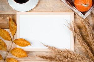 Autumn flat lay. Cup of hot espresso coffee and fallen yellow leaves on wooden background. Empty frame mock up for text. Morning concept. photo