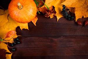 Autumn background. Frame from ripe pumpkins and fallen leaves on wooden boards. Harvest and Thanksgiving concept. photo