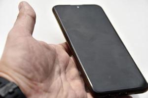 Black smartphone in hand on a white background. photo