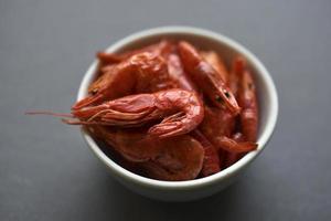 A delicious appetizer of red shrimp with spices. Peppered shrimp in a salad bowl on a black background. Spicy seafood appetizer. photo