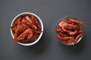 A delicious appetizer of red shrimp with spices. Peppered shrimp in a salad bowl on a black background. Spicy seafood appetizer. photo