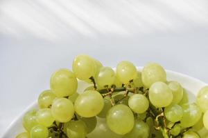 un racimo de uvas verdes en un primer plano de plato blanco. foto