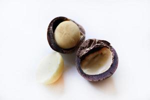 nuez entera y núcleo de macadamia sobre un fondo blanco. deliciosos frutos secos enteros. foto