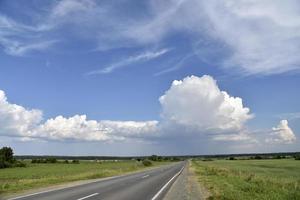 Thunderclouds on a summer day and a road in the countryside. A thunderstorm on a bright day. photo