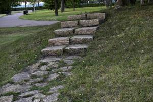 un camino de piedra en el parque y una escalera de granito con escalones. escalones de piedra en el jardín. foto