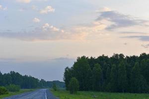 Evening landscape of green forest and multicolored clouds. Beautiful sunset with blue-pink clouds. photo