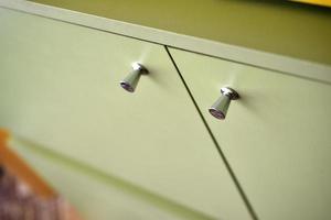 Green bedside table with silver handles indoors photo