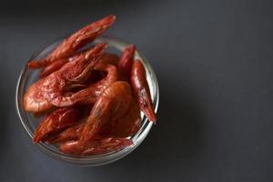 A delicious appetizer of red shrimp with spices. Peppered shrimp in a salad bowl on a black background. Spicy seafood appetizer. photo