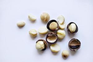 nuez entera y núcleo de macadamia sobre un fondo blanco. deliciosos frutos secos enteros. foto