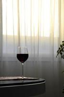 copa de vino tinto en la mesa mientras se pone el sol foto