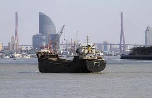 Shanhai, China - 12 September 2019 - A ship on the Huangpu river with parts of the city skyline in the background, slightly misty due to air pollution. photo