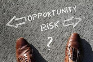 Top view on a man standing in front of the words Risk and Opportunity with arrows pointing to the left and right side of the picture photo