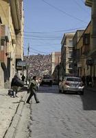 La Paz, Bolivia - June 2, 2018 - People crossing the steep streets of La Paz, Bolivia, with more red brick houses in the background. photo