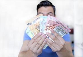 Young man holding up multiple Euro bills photo