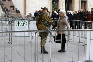 milán, italia - 14 de diciembre de 2018 - una anciana es cacheada por un soldado vestido con un uniforme de camuflaje antes de entrar a la catedral de milán. foto