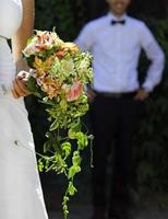 recién casados en un día soleado mientras la novia presenta su ramo de flores foto