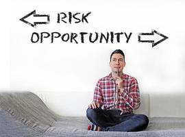 Man contemplating on couch, trying to decide between Risk and Opportunity photo