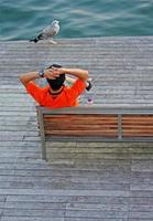 hombre con camiseta naranja relajándose en la bahía de barcelona foto