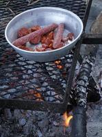 Hearty camping meal - grill with sausages on a metal plate photo