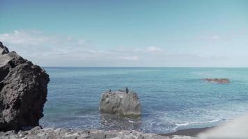 Waves crash on big rocks and shore line before an ocean horizon view video