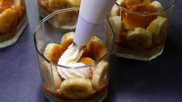 Closeup lady is making banoffee, putting whipped cream on top, homemade bakery concept video