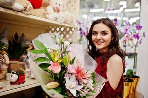 Brunette girl in red buy flowers at flower store. photo