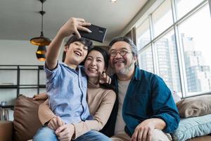 Family smiling at camera. Happy family taking a selfie, smiling at a phone at home. photo