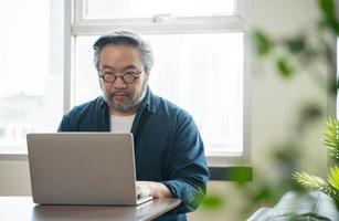 hombre asiático de mediana edad trabaja desde el concepto de hogar foto