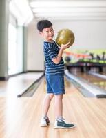 retrato lindo niño con pelota en el club de bolos foto