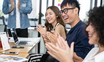 negocios asiáticos felices aplaudiendo después de una reunión de negocios exitosa en una oficina moderna foto