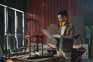 Young Asian man Carpenter working in woodcraft carpentry workshop. photo