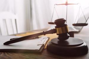 Justice and law concept.Male judge in a courtroom with the gavel, working with, computer and docking keyboard, eyeglasses, on table in morning light photo