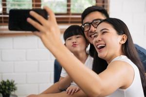 Happy family taking a selfie, smiling at a phone in their house photo