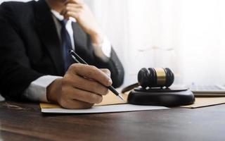 Justice and law concept.Male judge in a courtroom with the gavel, working with, computer and docking keyboard, eyeglasses, on table in morning light photo