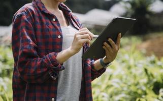 mujer agricultora de tecnología agrícola que sostiene tableta o tecnología de tableta para investigar sobre datos de análisis de problemas agrícolas e icono visual. foto