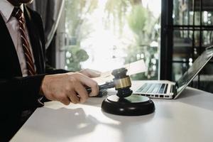 Justice and law concept.Male judge in a courtroom with the gavel, working with, computer and docking keyboard, eyeglasses, on table in morning light photo