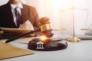 Justice and law concept.Male judge in a courtroom with the gavel, working with, computer and docking keyboard, eyeglasses, on table in morning light photo