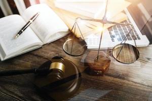 Justice and law concept.Male judge in a courtroom with the gavel, working with, computer and docking keyboard, eyeglasses, on table in morning light photo
