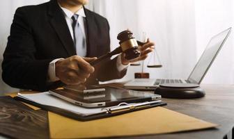 Justice and law concept.Male judge in a courtroom with the gavel, working with, computer and docking keyboard, eyeglasses, on table in morning light photo