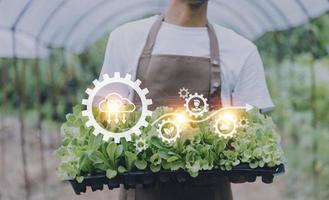 un hombre de negocios futurista cultiva verduras y cultivos usando tecnología moderna de inteligencia artificial usando teléfonos móviles, sensores de temperatura y humedad, rastreo de agua, control climático, íconos de datos holográficos. foto