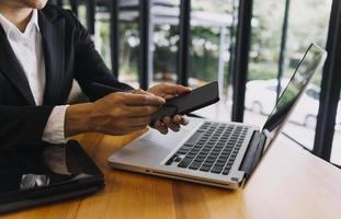 hombre de negocios y equipo analizando la tarea financiera de los estados financieros. con teléfono inteligente y computadora portátil y tableta. concepto de gestión de riqueza foto