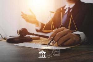 Justice and law concept.Male judge in a courtroom with the gavel, working with, computer and docking keyboard, eyeglasses, on table in morning light photo