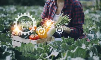 un hombre de negocios futurista cultiva verduras y cultivos usando tecnología moderna de inteligencia artificial usando teléfonos móviles, sensores de temperatura y humedad, rastreo de agua, control climático, íconos de datos holográficos. foto