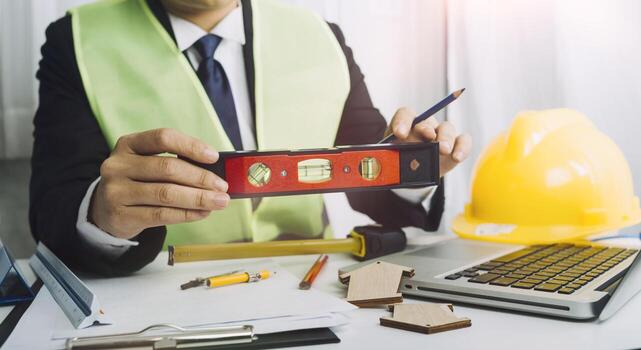Two colleagues discussing data working and tablet, laptop with on on architectural project at construction site at desk in office photo