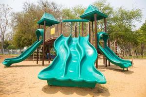 Green playground on yard in the park with tree photo